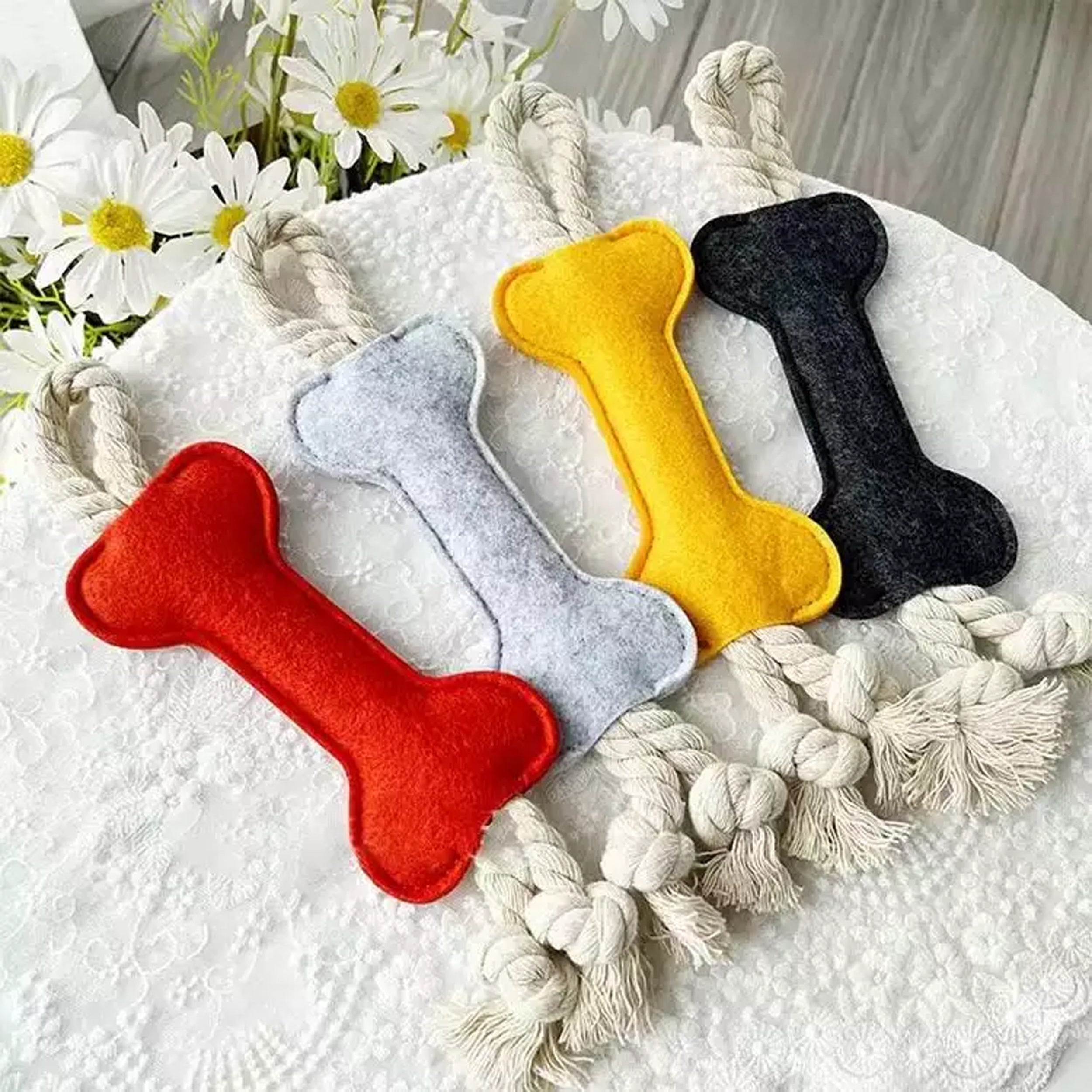 felt bone shape dog chew toy with rope on table