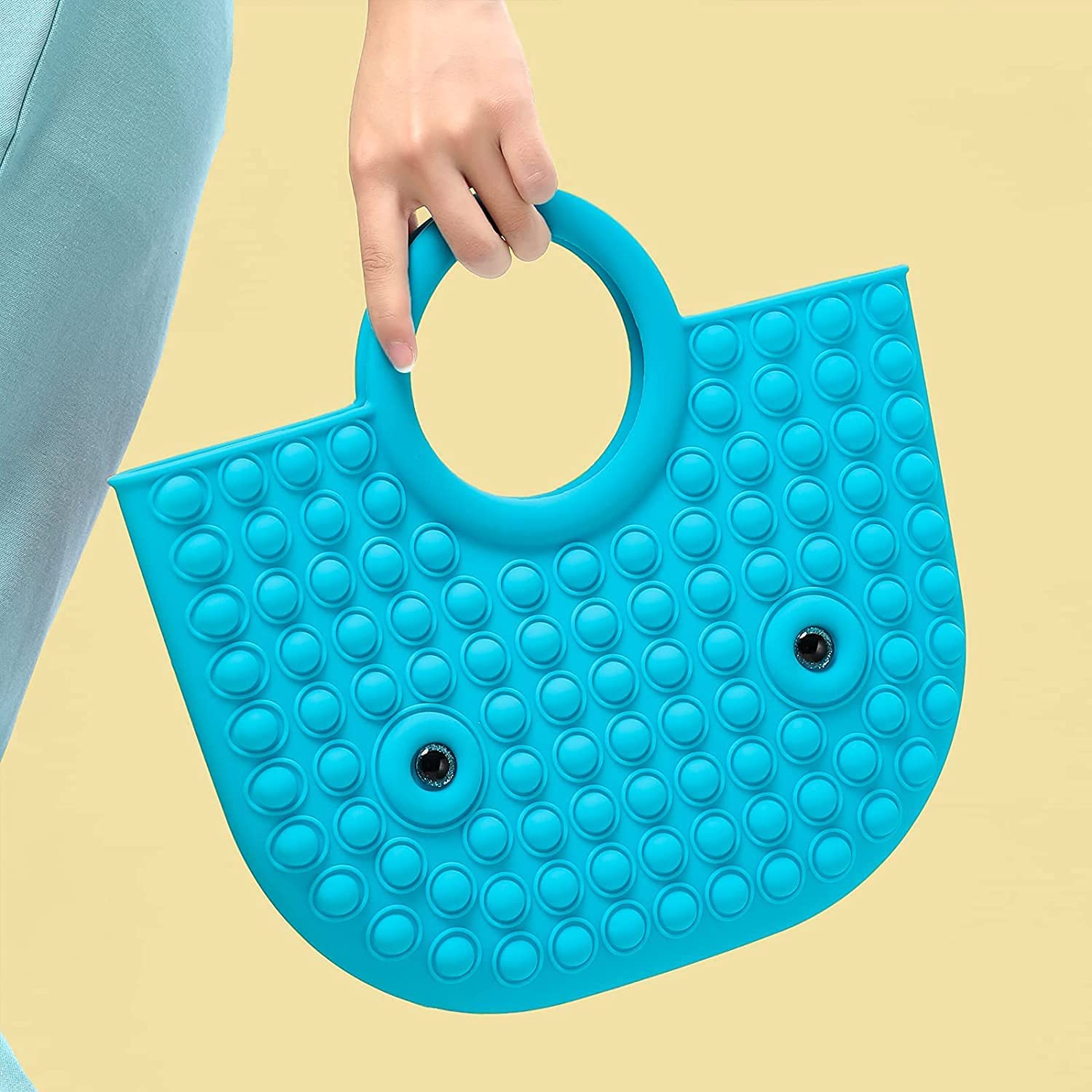 blue pop it fidget handbag in hands of a model with yellow background
