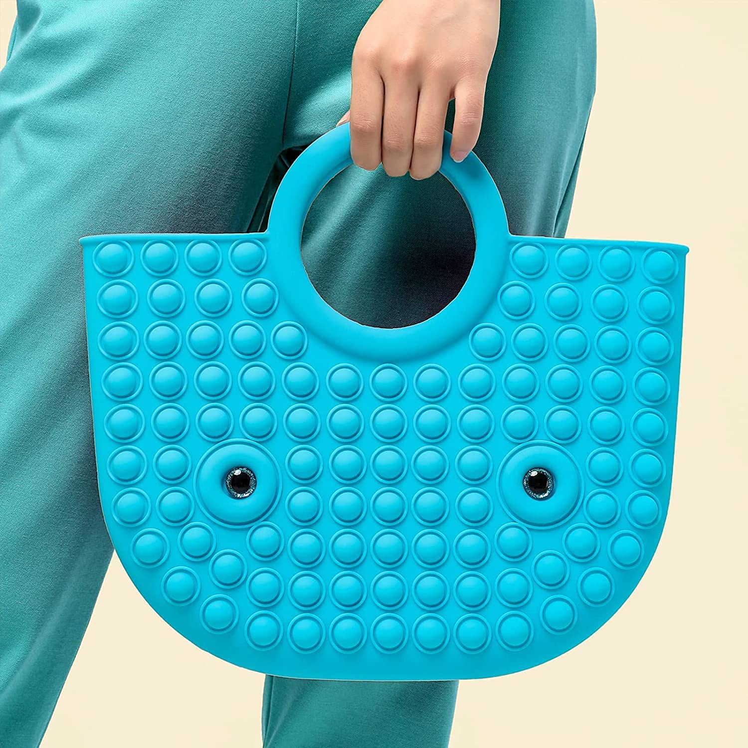 blue pop it fidget handbag in hands of a model wearing green pants with yellow background